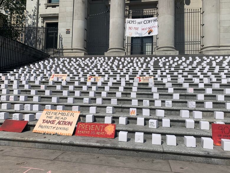 Signs sit on grand steps, calling for action on heat deaths.