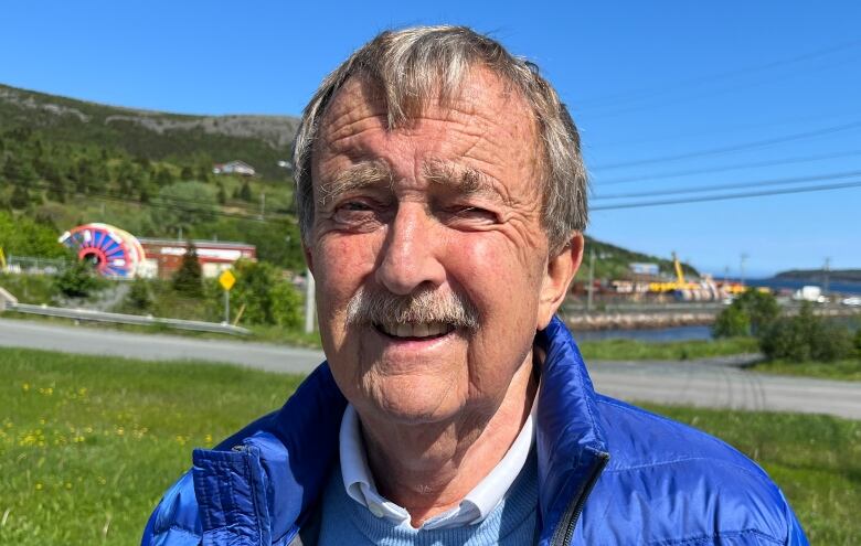 a portrait style photo of oil industry analyst Rob Strong, with the marine base in Bay Bulls as a backdrop.