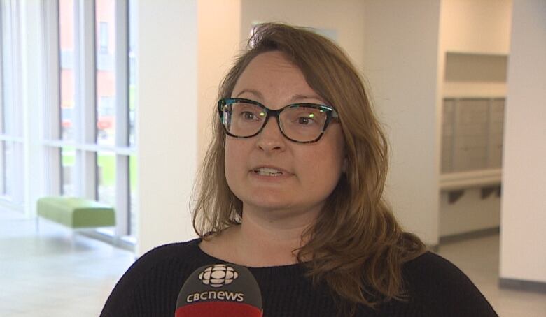 Woman with long hair speaks into a CBC microphone