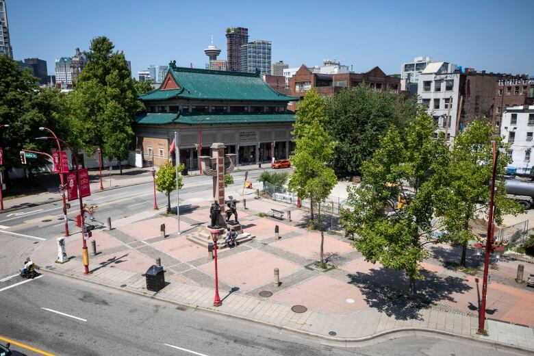 A tall monument is pictured from a bird's eye view, next to a parking lot and a Chinese-style building.