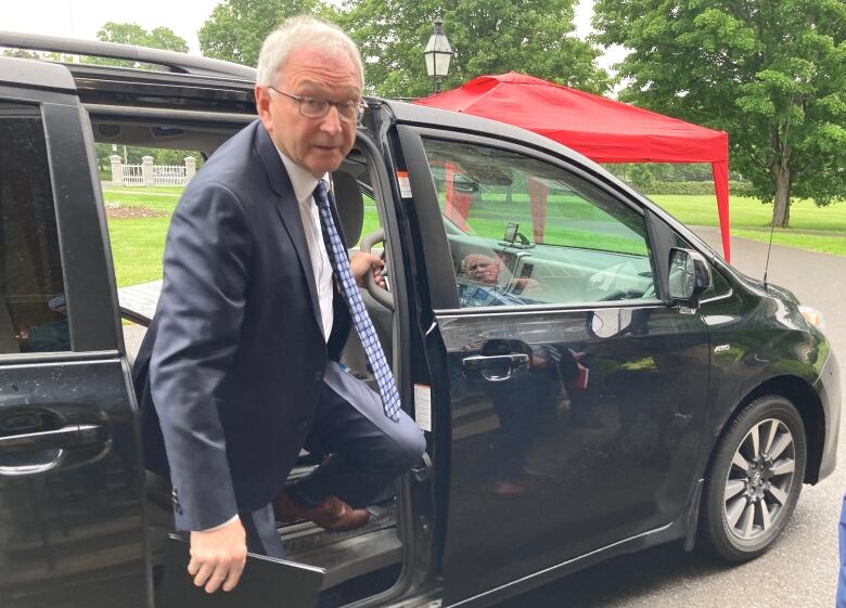 Man in blue suit stepping out of black car