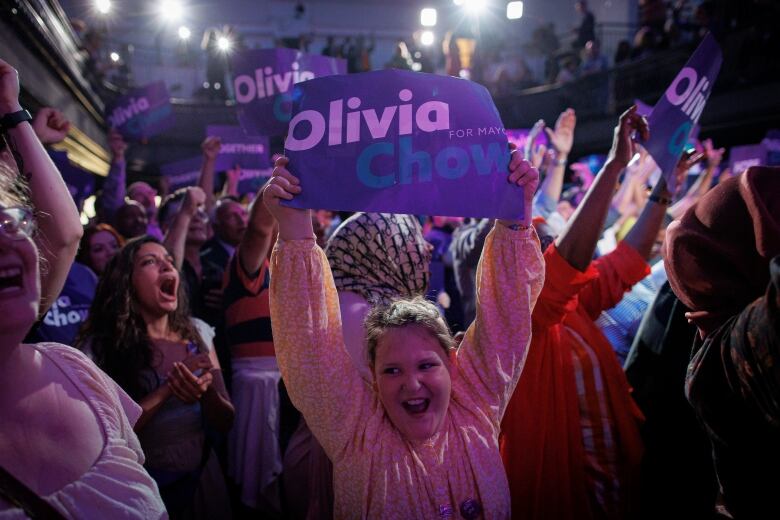 Supporters some holding posters that say Olivia Chow for mayor react at an election night event.