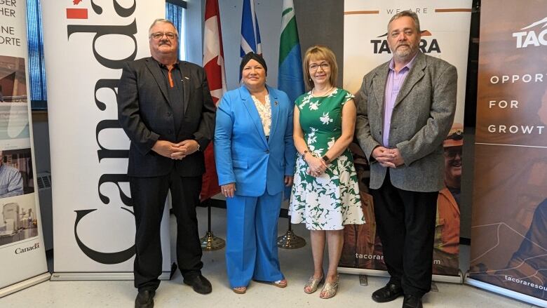 A group of people stand in front of banners that say Canada, and Tacora Resources. 