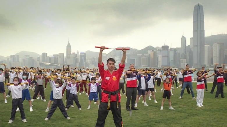 People do an martial arts demonstration on grass.