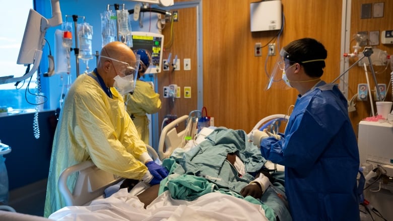 A doctor is seen treating a patient in a hospital bed.