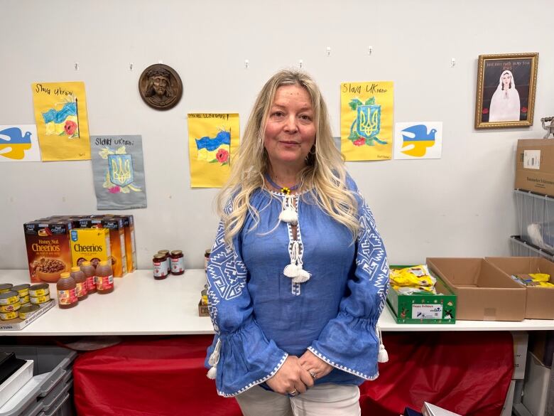 A woman in a blue shirt stands in front of boxes of food