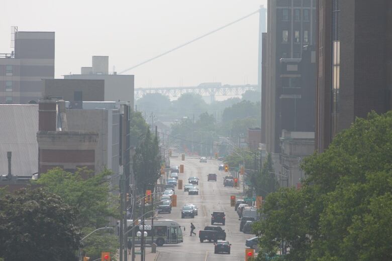 Smoke casting a haze over a busy street filled with cars and pedestrians