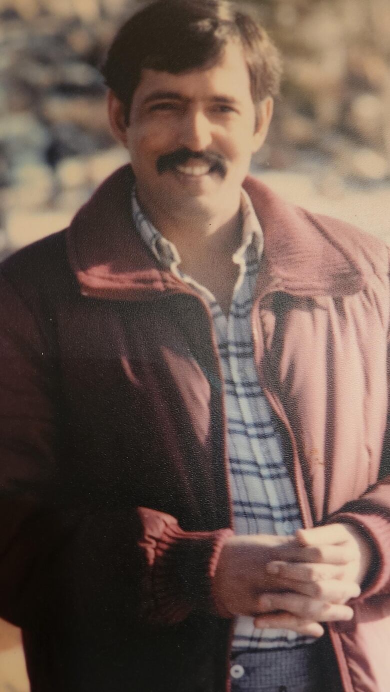 An old photo of a man with a mustache smiling outdoors. 