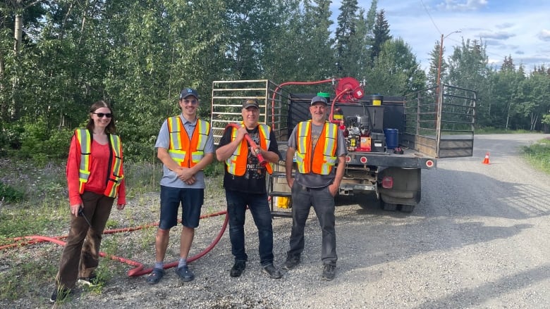 Four people standing together infront of a truck.