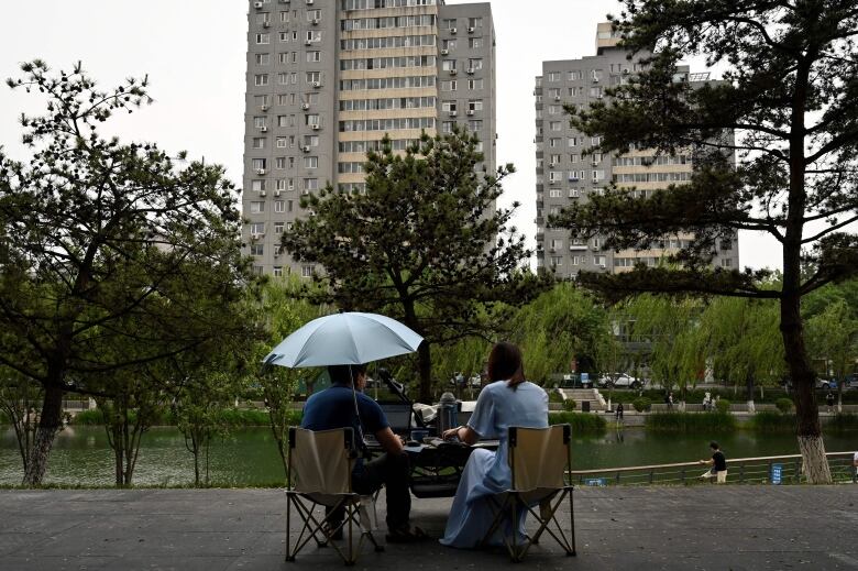 People work on laptops in Beijing, near the Liangma river, in May 2022.