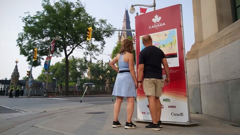 Two people look at a map on a downtown street corner.