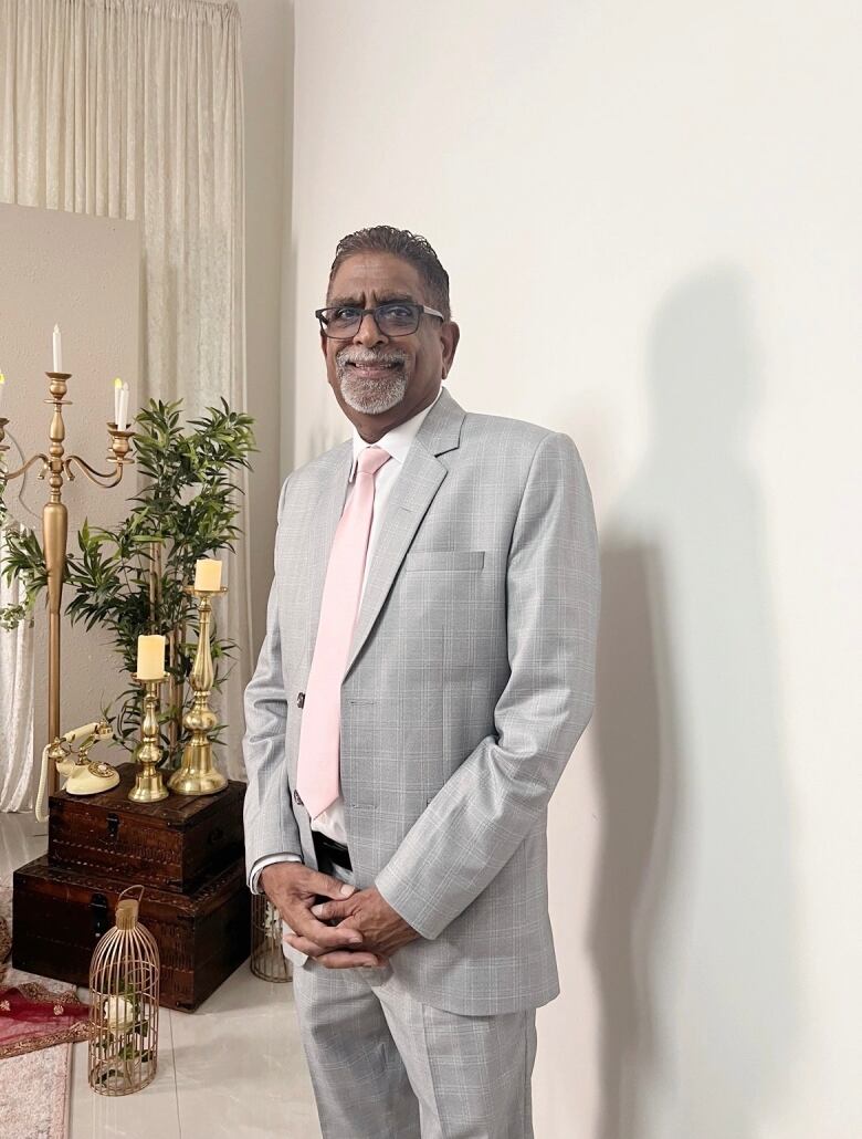 A South Asian man poses for a picture wearing a grey suit.