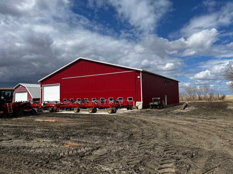 A red barn can be seen on a farm on a sunny day. 