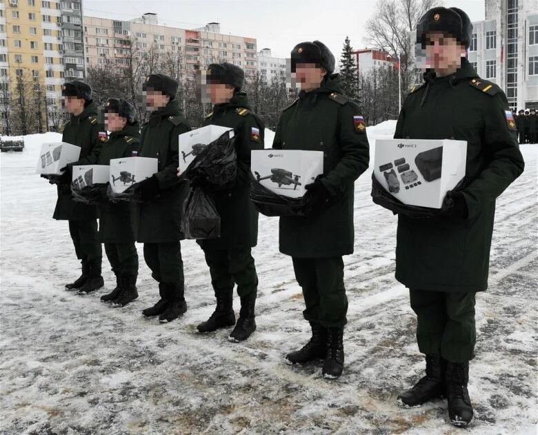 Members of the White Raven patriotic group display drones and accessories which they donated to a Russian brigade in November 2022. This picture was taken from one of the group's social media accounts, and it included the pixelation of the faces. 