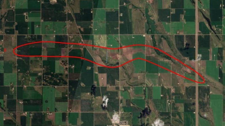 A satellite image shows a dark line where a tornado cut through farmland in a rural area north of Calgary. 