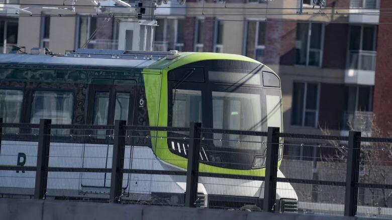 Green, black and white train advances on tracks. 