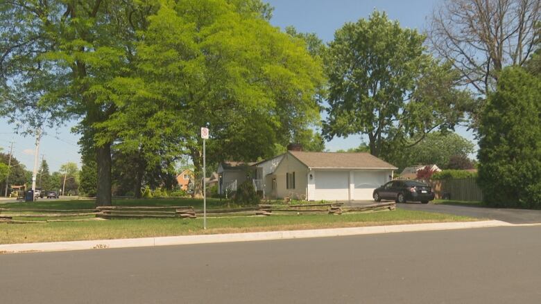 A picture of a lawn and a house with a car in the driveway