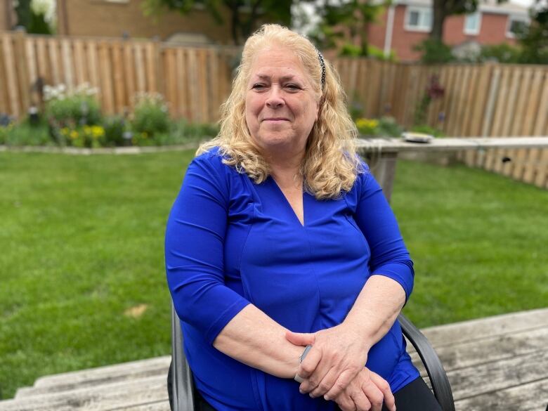 A woman wearing blue sits in a chair.