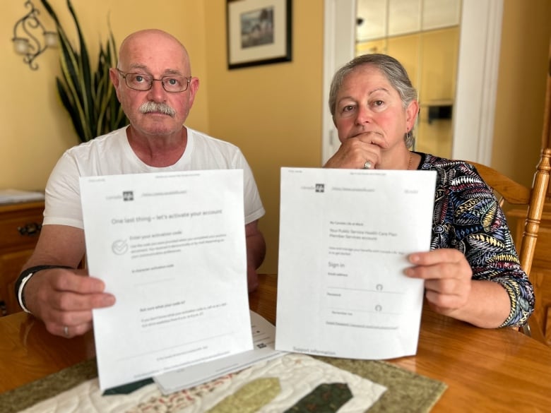 A man and woman hold up papers.