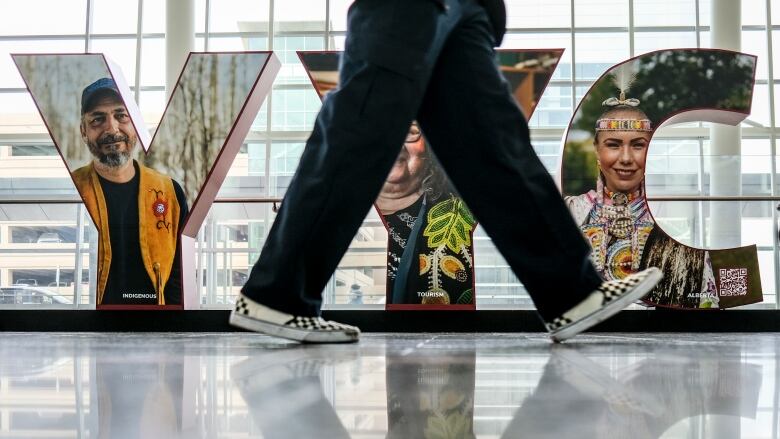 A man's legs are pictured walking past three big letters that read YYC.