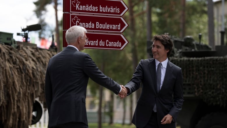 Prime Minister Justin Trudeau and Latvian Prime Minister Krisjanis Karins shake hands after unveiling a street sign honouring Canada at the Adazi Military base, Monday, July 10, 2023 in Adazi, Latvia.