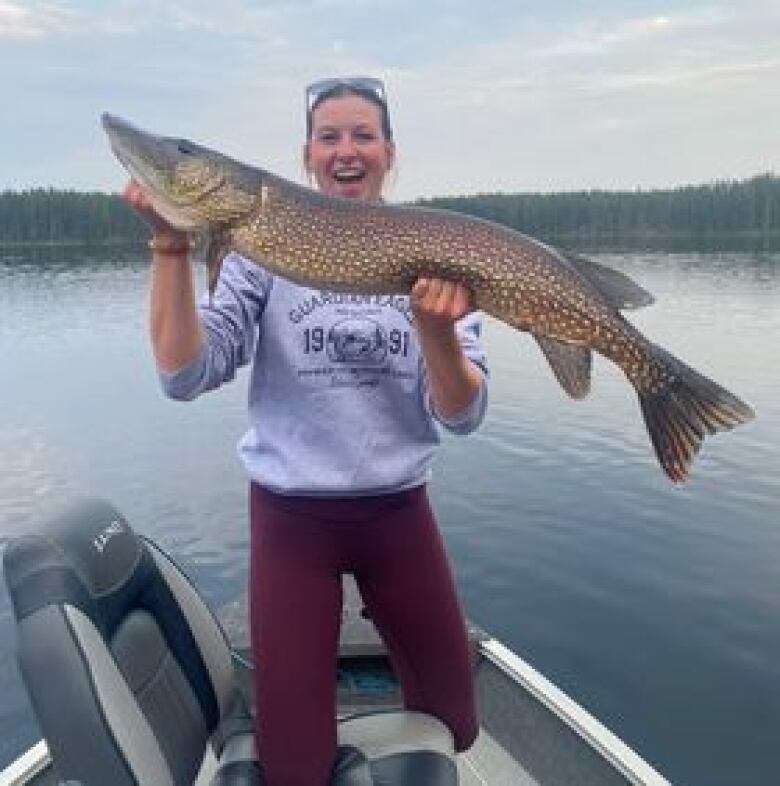 A woman poses for a picture with a fish. 