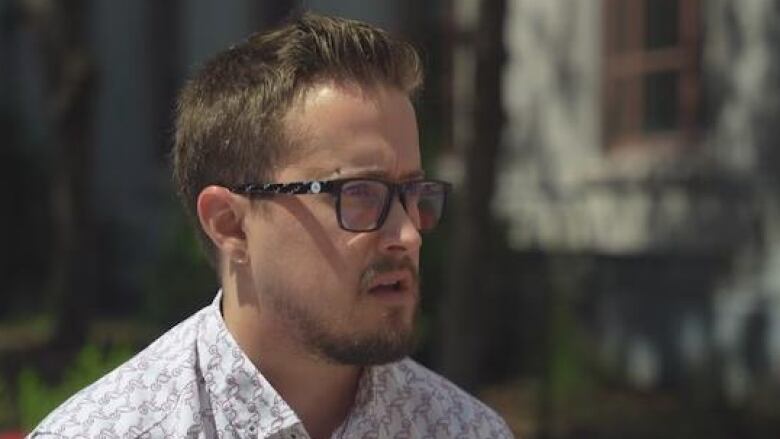 A man gives an interview outside in summer.