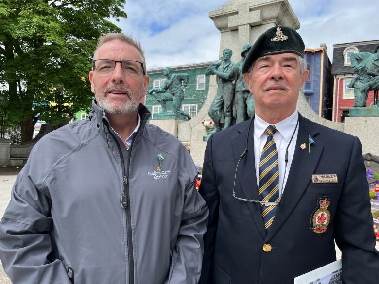 Two men, one dressed in a legion uniform, poses in front of the national war memorial in St. John's.