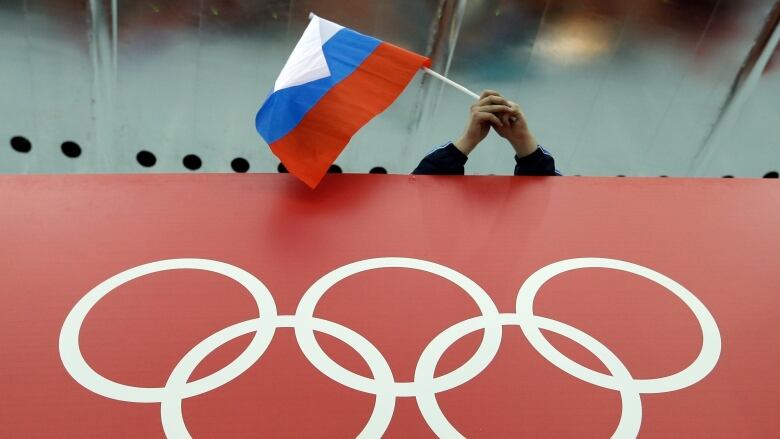 A Russian flag is waved above the Olympic logo.