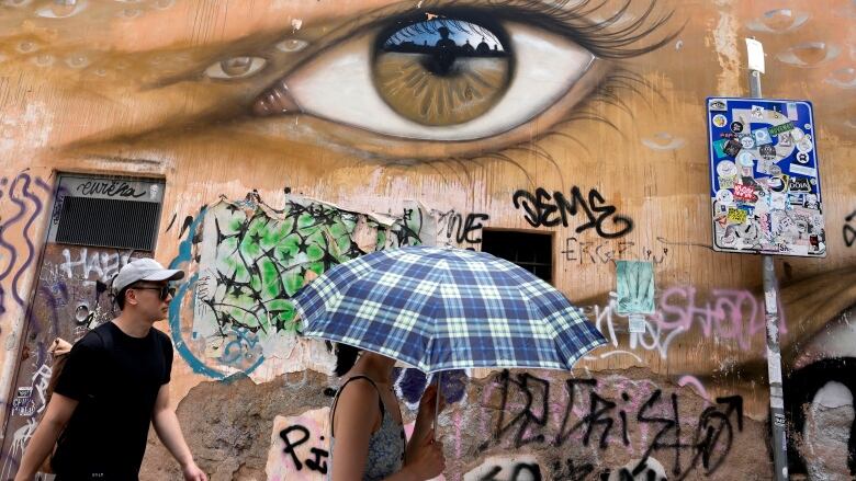 A woman uses an umbrella to take shelter from the sun as she walks in downtown Rome