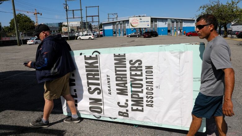 Union members with the International Longshore and Warehouse Union Canada (ILWU) remove a strike sign from a picket line outside the despatch hall in Vancouver