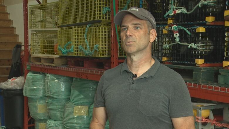 A man stands in front of lobster traps.