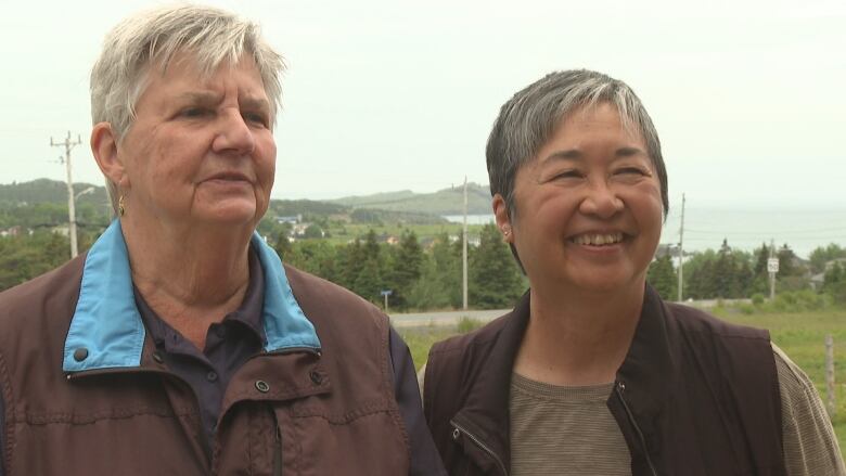 Two women are smiling outdoors.