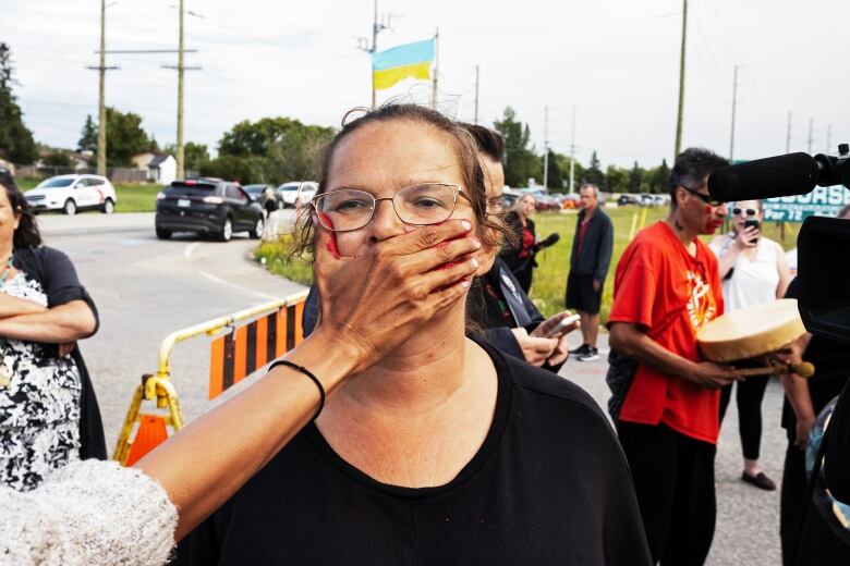 A woman places her hand over another woman's face.