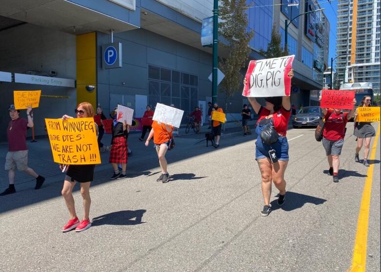 People holding signs walk down a street.