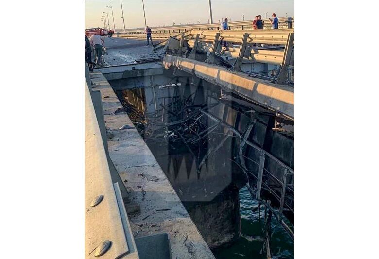 A view of a damaged bridge is shown, looking down over the water.