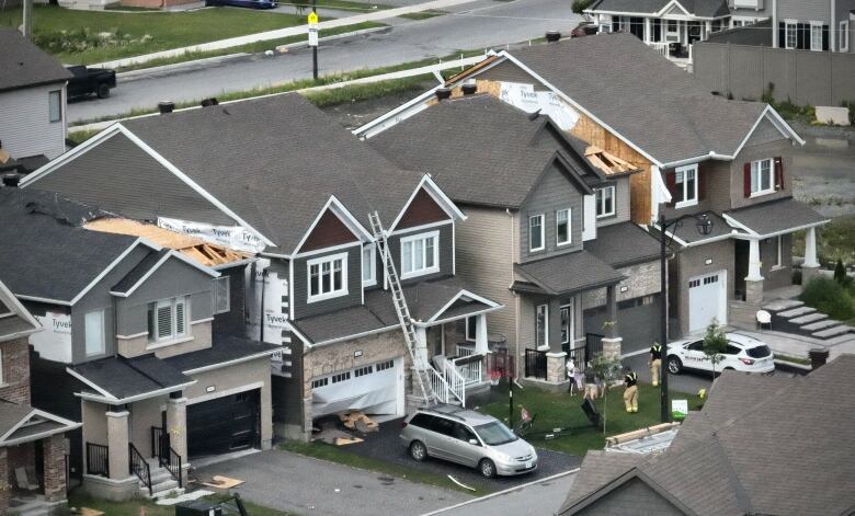 A row of homes in summer with damaged windows and roofs because of strong winds.