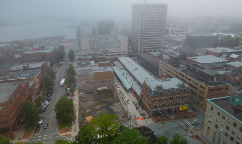 Drone picture of an empty lot with a giant hole in the ground waiting for construction. Taken on a foggy day. 