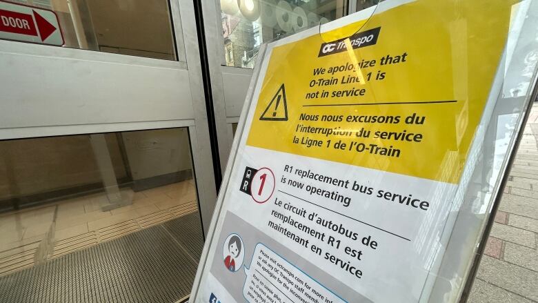 A yellow and white sign outside a light rail station apologizes that trains are not running and tells riders where to get a bus.