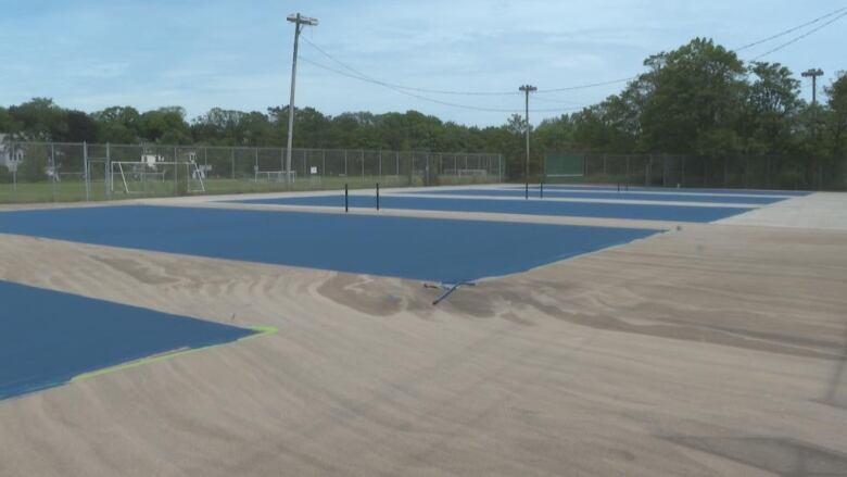 Six freshly painted blue courts bask in the sun at the St. John's tennis club. 