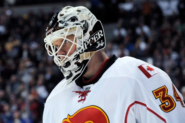 A close up of a hockey goalie wearing his mask. The side of the mask is painted with the player's nickname, Kipper, and his number thirty-four.