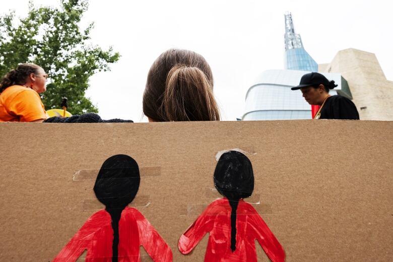 The back of a woman's head is seen in front of a sign with two women wearing red dresses.