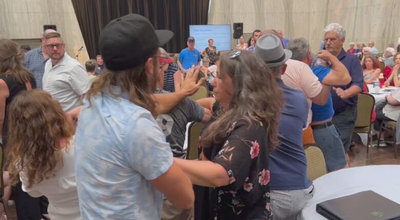 After Housing Minister Rob Lantz was shoved at the meeting, others in the crowd pulled a man away from him in a scene of chaos.