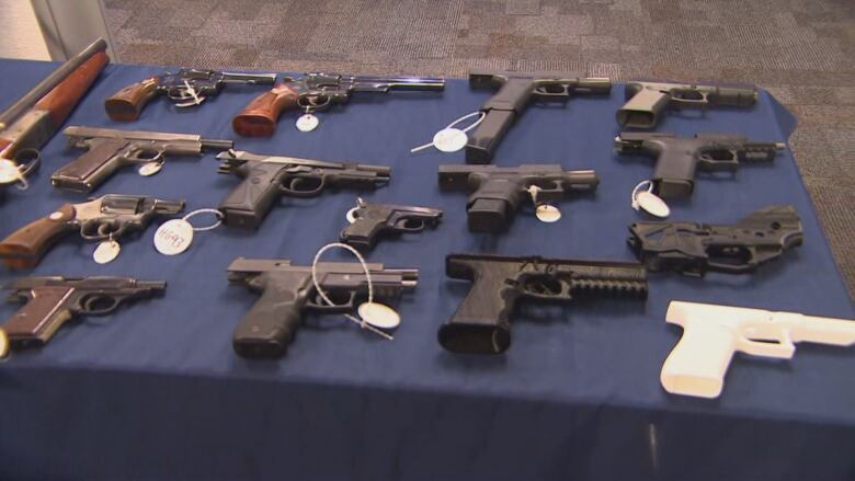 A collection of handguns sits on a table with a blue cloth