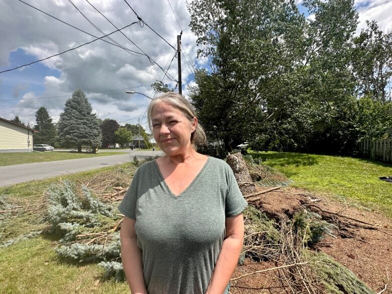 A woman stands in front of a tree that lies on the ground. 