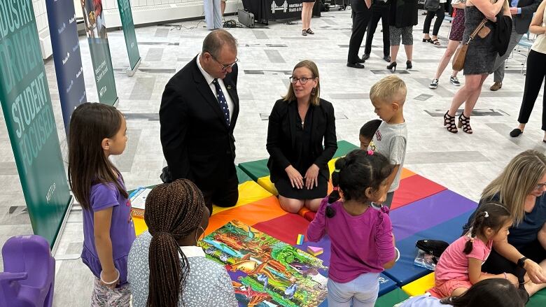 Children play on a play mat. Two ministers sit with them.