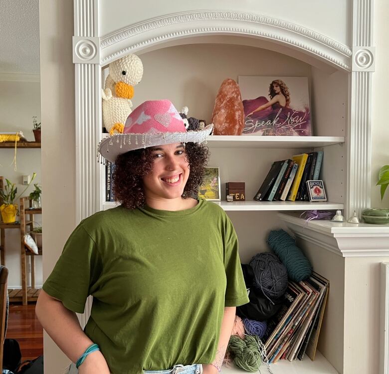 A woman wearing a green shirt and a pink cowboy hat smiles