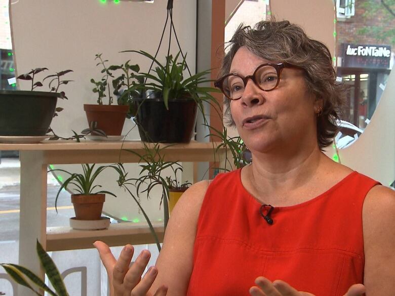 a woman with short hair, thick black round glasses, and red shirt talking to the camera.