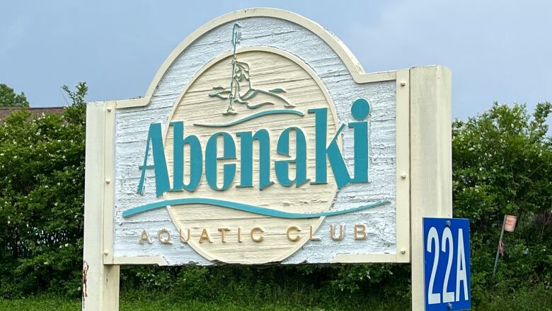 A large wooden beige, turquoise and gold sign reads 'Abenaki Aquatic Club.'