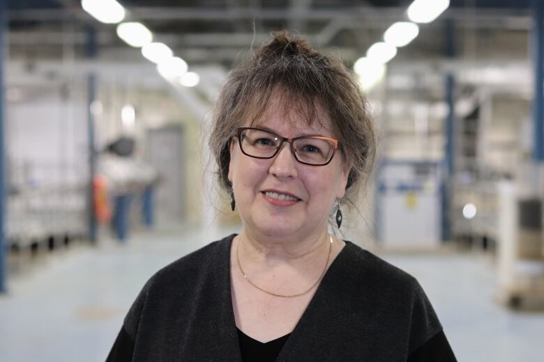 A woman wearing glasses in a black shirt smiling. 